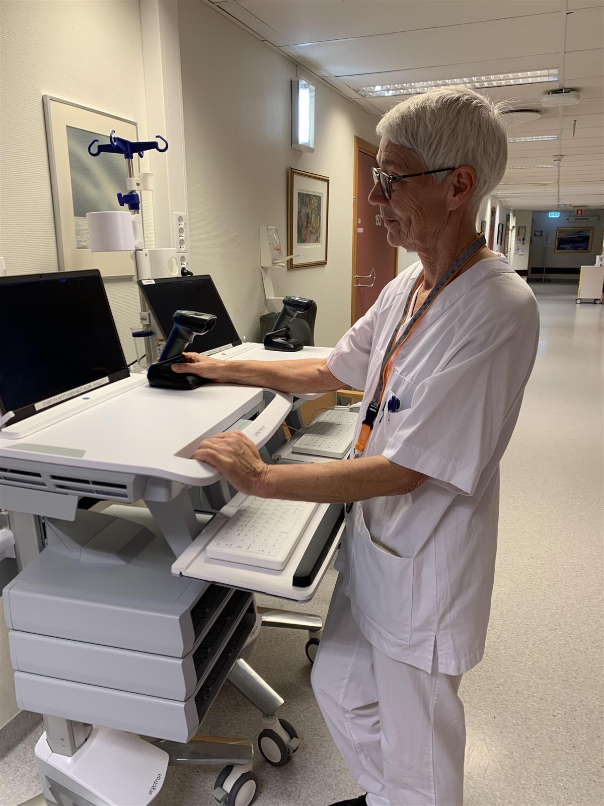Dame i sykepleieruniform står ved maskin - Klikk for stort bilde